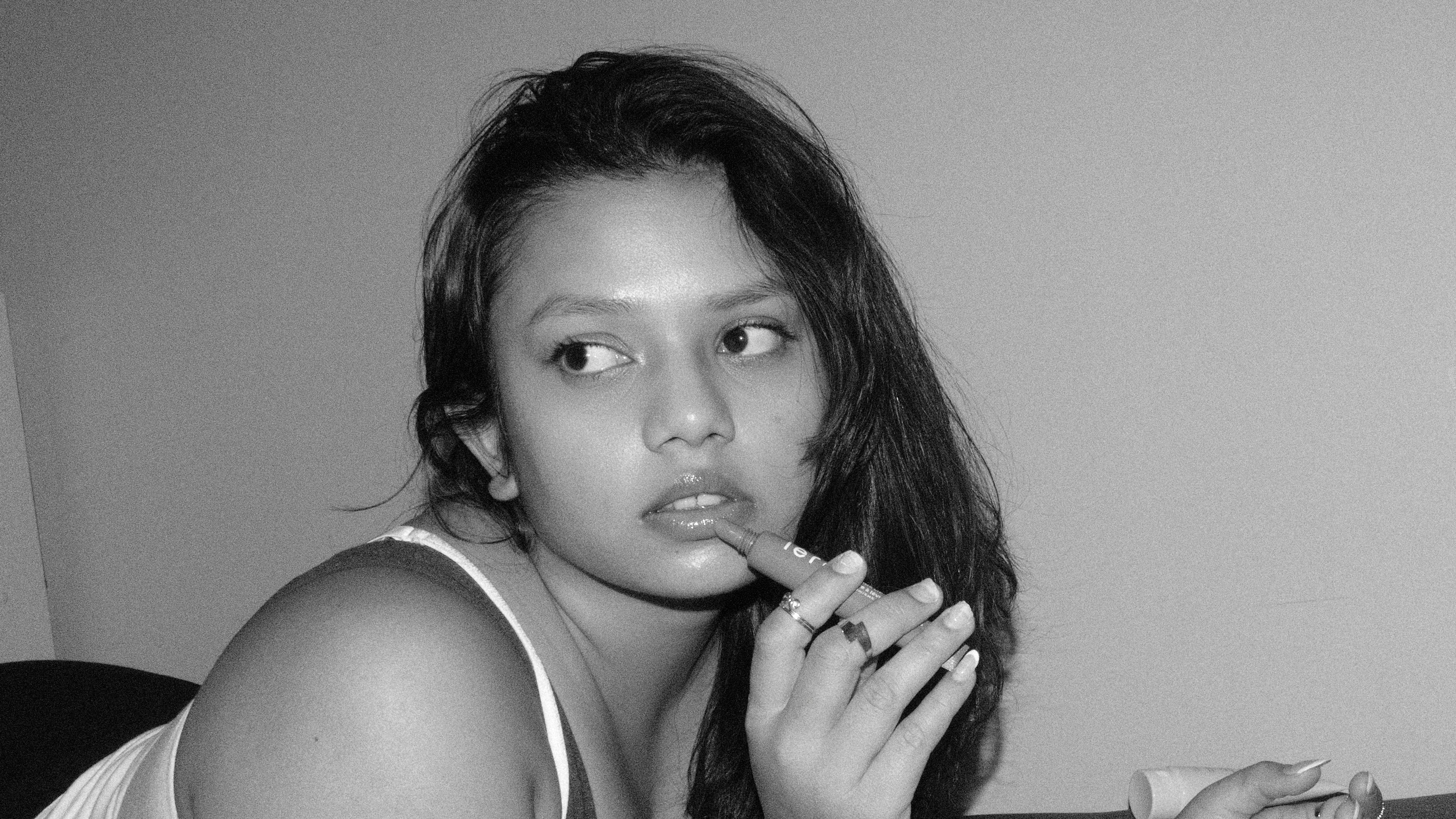 Black-and-white portrait of a woman applying LÉRA Peptide Lip Butter